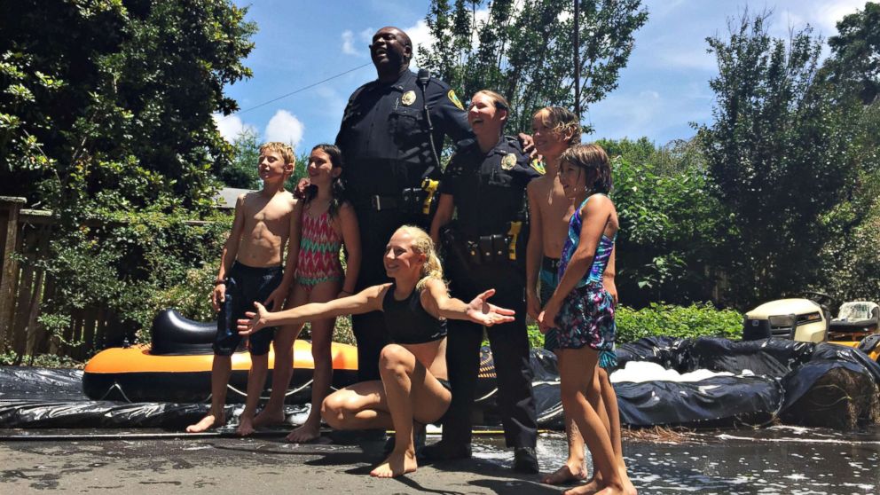 PHOTO: Children from the neighborhood pose with Asheville, North Carolina, police officers after riding down the slip 'n slide, July 2, 2017. 