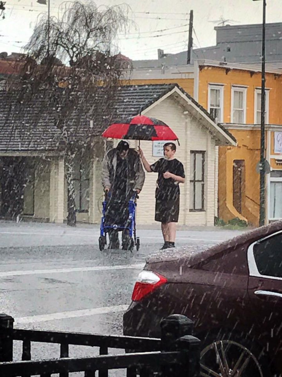 PHOTO: Elvis Ingersoll, 14, rushed out to hold an umbrella over the elderly man's head in Vallejo, California.