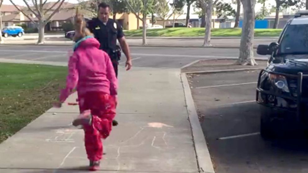 Officer Zach Pricer with the Huntington Beach Police Dept. showed an 11-year-old girl how to play hopscotch, March 30, 2016, while another officer worked on getting housing arrangements for the girl and her mother who'd been living out of a car. 

