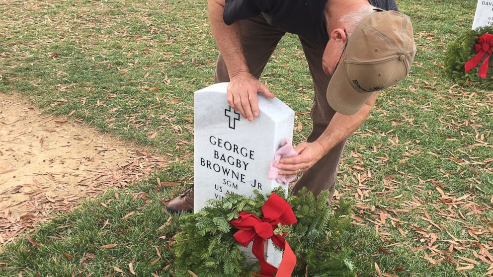 Wayne Eure cleans off a headstone at Arlington National Cemetery on National Wreaths Across America Day.