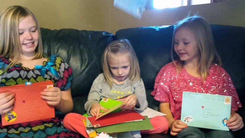 Addie Fausett, center, and her sisters Shaley Fausett, left, and Audree Fausett, right, open Christmas cards sent to them from strangers around the world.
