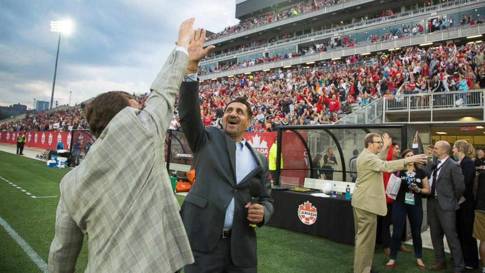 The Honourable Bal Gosal, Federal Minister of Sport, high-fives with Mike Wallace, MP Burlington, during the UNICEF Canada's attempt to break a Guinness World Record for the greatest number of people simultaneously doing high-fives during the half-time of the Women's World Cup Soccer friendly match between Canada and England at Tim Horton's Field in Hamilton, Ontario, May 29, 2015.