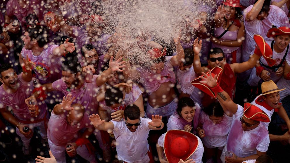 Revellers celebrate while waiting for the launch of the 'Chupinazo' rocket, to celebrate the official opening of the 2019 San Fermin fiestas with daily bull runs, bullfights, music and dancing in Pamplona, Spain, Saturday July 6, 2019. (AP Photo/Alva