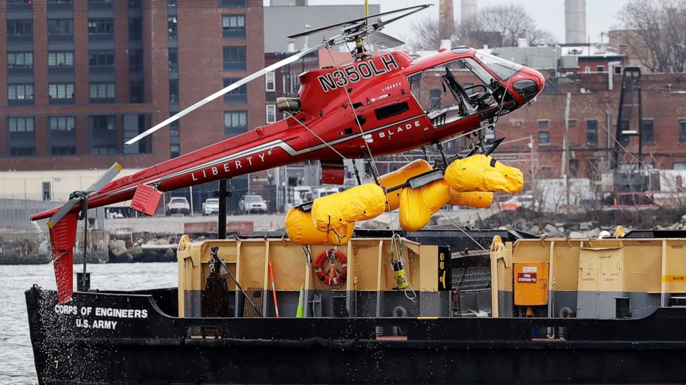 FILE - In this March 12, 2018 file photo, a helicopter, which crashed the previous day, is hoisted by crane from the East River onto a barge, in New York. The helicopter company, FlyNYON, exploited a regulatory loophole to avoid stricter safety requi