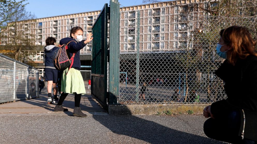 FILE - In this Thursday, April 1, 2021 file photo, Emma Woodroof waves goodbye to her mother Julie as she enters her school in Strasbourg, eastern France. Children, parents and teachers are battling with connection problems across France after an abr