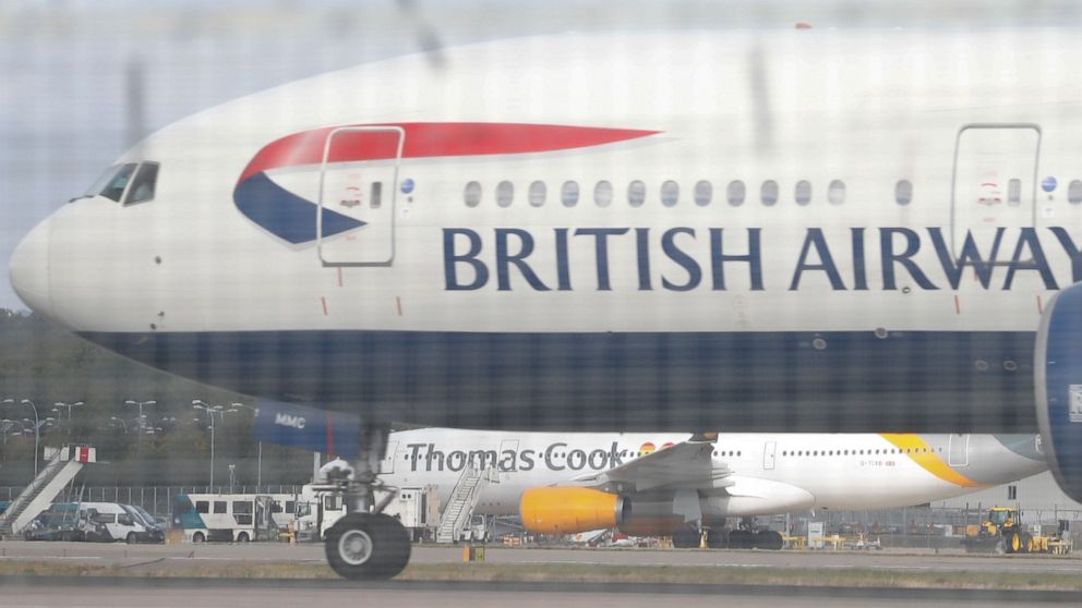 Seen though a perimeter fence a British Airways aircraft takes off past a Thomas Cook plane in the background at Gatwick Airport, England, Monday, Sept. 23, 2019. British tour company Thomas Cook collapsed early Monday after failing to secure emergen