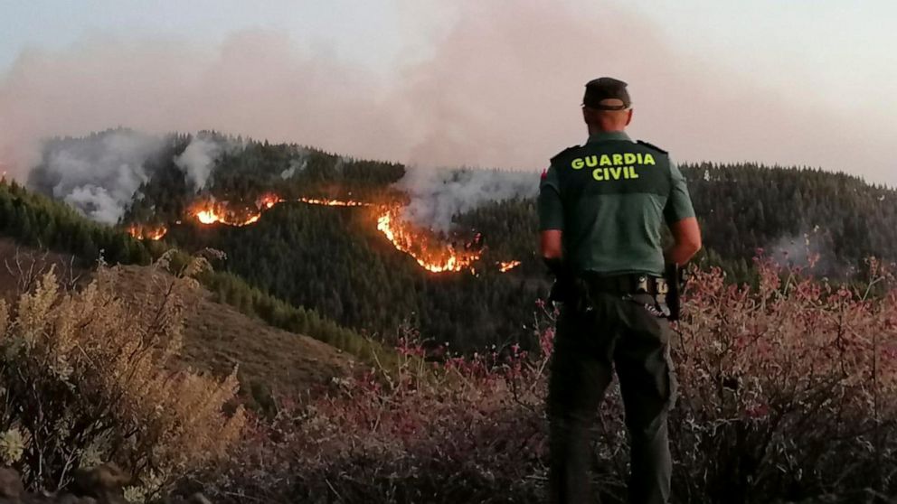 In this photo issued by the Guardia Civil, an officer looks at a forest fire in Gran Canaria, Spain, on Saturday Aug. 11, 2019. Spanish authorities say a wildfire on the Canary Island of Gran Canaria has burned 1,000 hectares (2,470 acres) and has fo