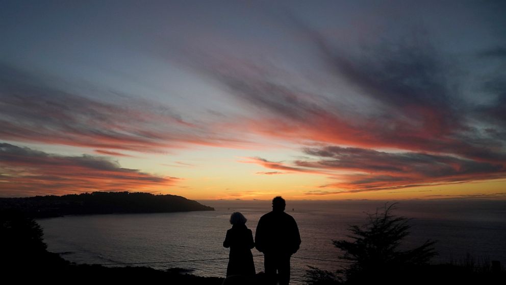 FILE - In this Dec. 21, 2020, file photo people watch as the sun sets from the Presidio in San Francisco. Rising inflation is expected to lead to a sizeable increase in Social Security's annual cost-of-living adjustment, or COLA, for 2022. Exactly ho