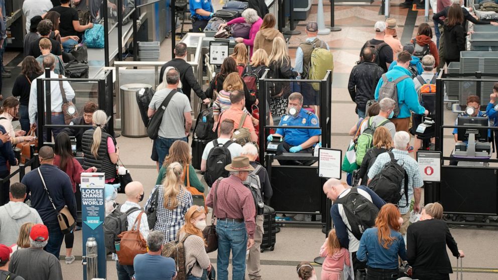 FILE - Travelers queue up move through the north security checkpoint in the main terminal of Denver International Airport, Thursday, May 26, 2022, in Denver. Airline travelers are not only facing sticker shock this Memorial Day weekend, the kick off 