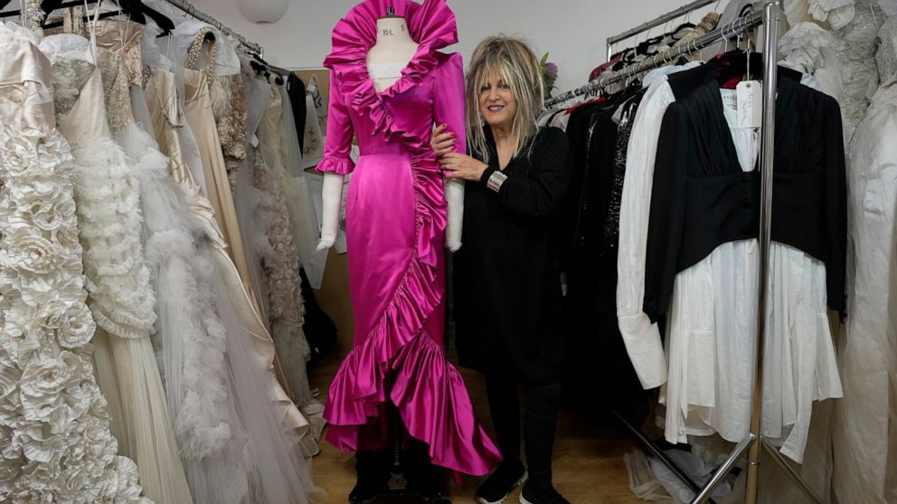 British designer Elizabeth Emanuel stands beside a replica of an evening gown she designed for the then Lady Diana Spencer to wear at a Buckingham Palace party a few days before her marriage to Prince Charles in 1981, in London, Friday, Nov. 18, 2022