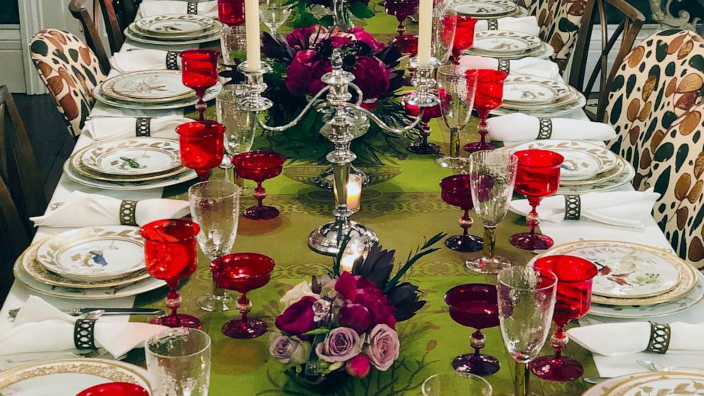 This photo provided by interior designer Elizabeth Stuart shows a table setting design by Stuart in a residence in Charleston, S.C. When setting a beautiful holiday table, consider using several small, low centerpieces rather than one large one, as s