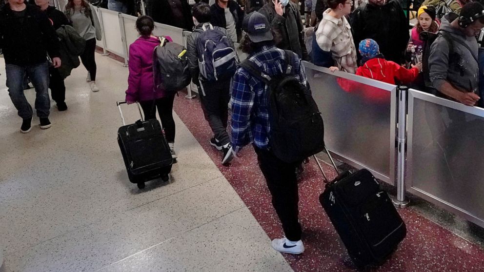 Travelers wheel the bags past the line for TSA screening in Terminal B at Logan International Airport, Monday, Nov. 21, 2022, in Boston. Travel experts say the ability of many people to work remotely is letting them take off early for Thanksgiving or