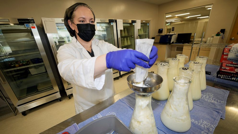 Rebecca Heinrich, director of the Mothers' Milk Bank, loads frozen milk donated by lactating mothers from plastic bags into bottles for distribution to babies Friday, May 13, 2022, at the foundation's headquarters in Arvada, Colo. (AP Photo/David Zal