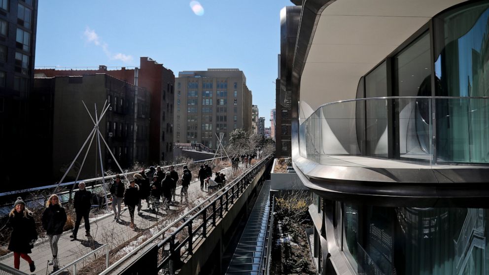 In this March 5, 2019 photo, structures both modern and old flank visitors walking on the High Line park in New York. An estimated 8 million visitors a year now visit the park, which threads 1.5 miles through an utterly transformed part of Manhattan 