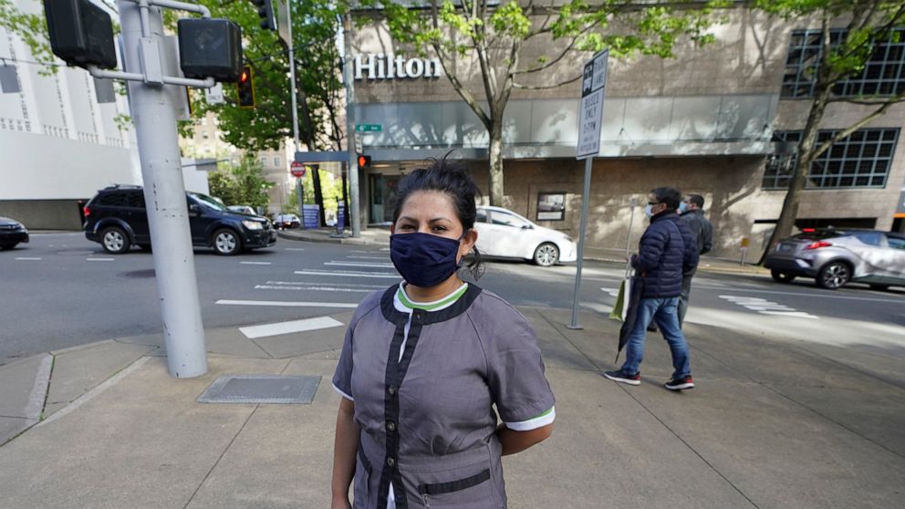 Sonia Guevara poses for a photo, Wednesday, May 18, 2022, outside the Hilton hotel where she works as a housekeeper in downtown Seattle. Many hotels across the United States have done away with daily housekeeping service, making what was already one 