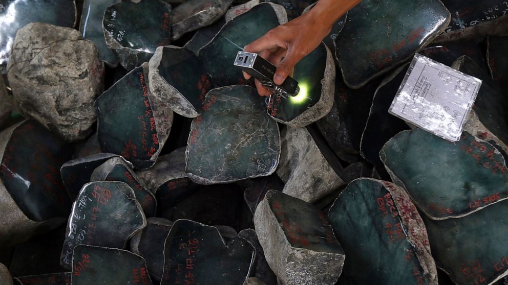 FILE - A merchant examines a jade stone displayed at the Gems Emporium in Naypyitaw, Myanmar on Nov. 13, 2018. Human rights activists are lobbying major jewelers to stop buying gems sourced in Myanmar as a way to exert pressure on Myanmar’s military 