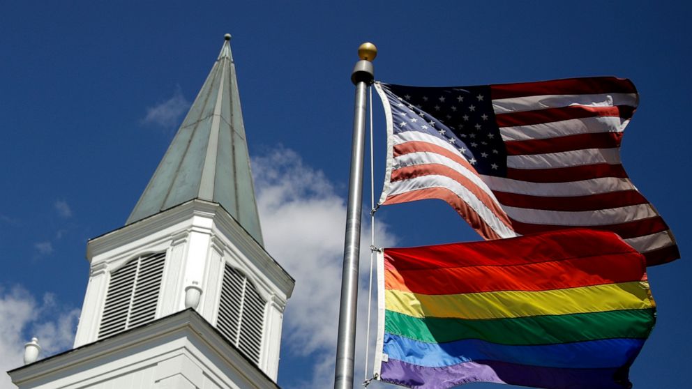 FILE - A gay pride rainbow flag flies along with the U.S. flag in front of the Asbury United Methodist Church in Prairie Village, Kan., on April 19, 2019. The United Methodist Church's Council of Bishops, ending a five-day meeting on Friday, April 29