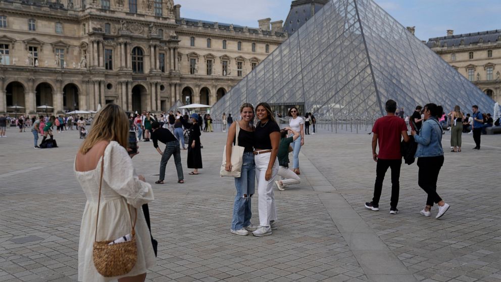 FILE - Tourists take pictures in front of the Pyramid in the Louvre Museum courtyard in Paris, France, on June 20, 2022. Travel to Europe might be an attractive option to travelers looking for a budget vacation in 2022. The dollar is strong this year
