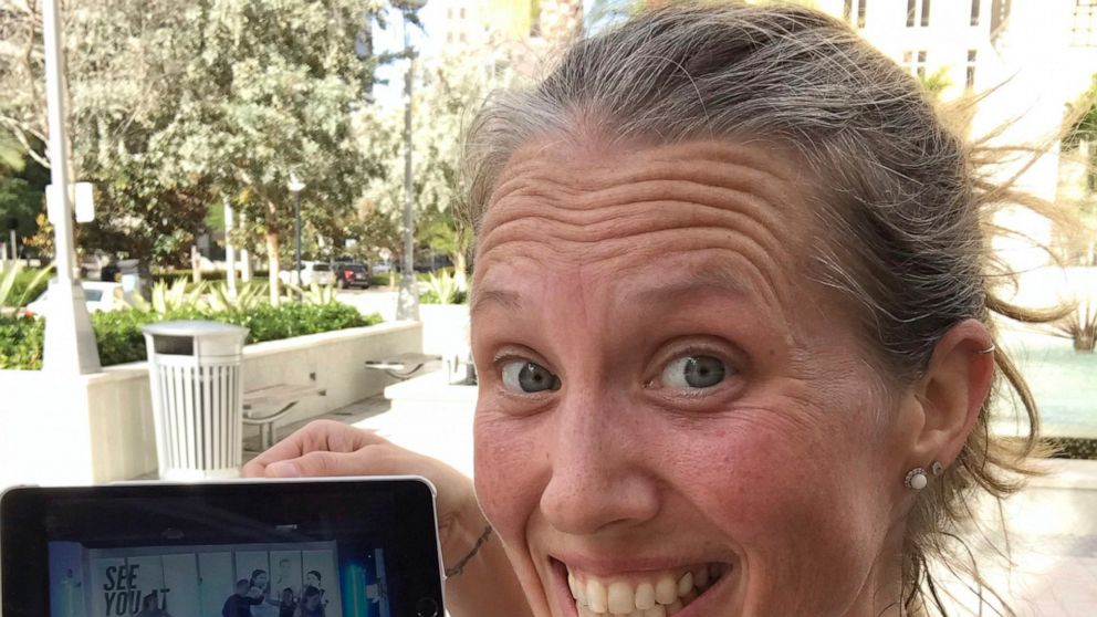 In this selfie provided by Beth Berglin, she shows a screen where she joins a Burn Boot Camp live stream workout from her home Thursday, March 19, 2020, in Coral Gables, Fla. People around the country who are self-isolating or maintaining social dist