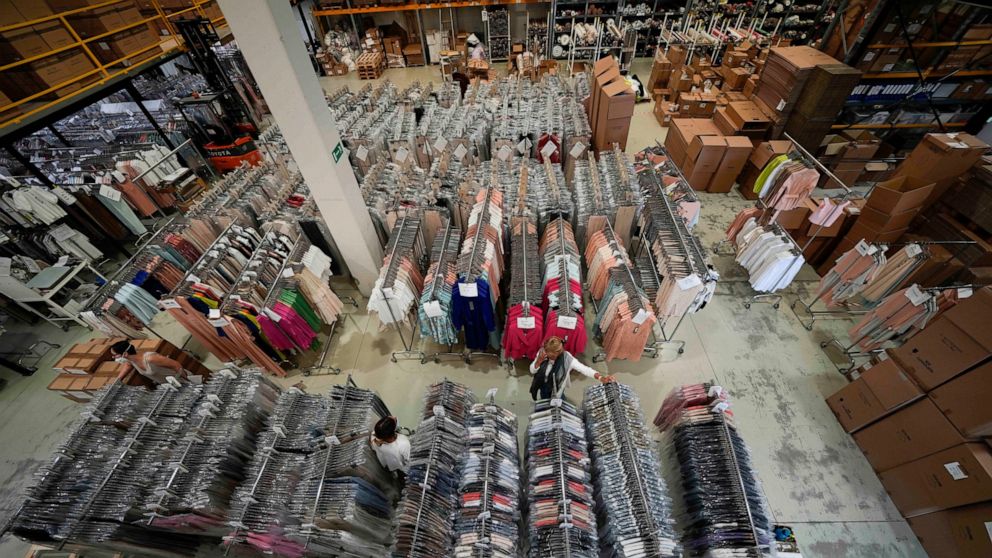 Nadia Zanola, right, chairman of the 'Cose di Maglia' factory, goes through racks of clothing at a warehouse section of unsold clothes, in Brescia, Italy, Tuesday, June 14, 2022. Small Italian fashion producers are still allowed to export to Russia, 
