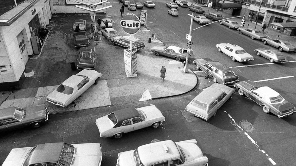 FILE - Cars line up in two directions at a gas station in New York City, on Dec. 23, 1973. An unhappy confluence of events has economists reaching back to the days of disco and the bleak high-inflation, high-unemployment economy of nearly a half cent