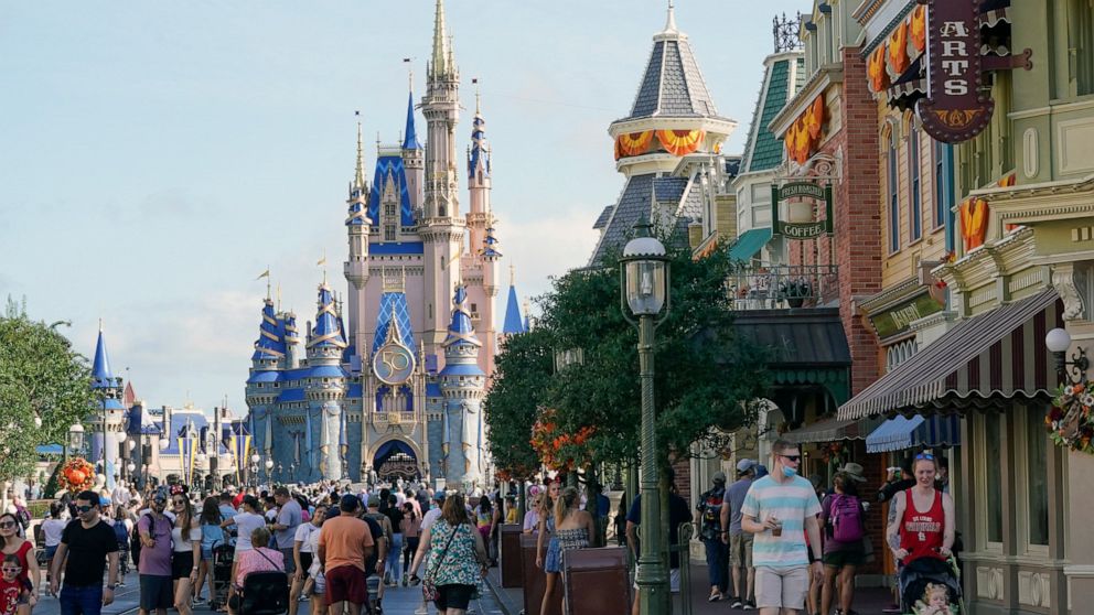 FILE - Guests stroll along Main Street at the Magic Kingdom theme park at Walt Disney World, Monday, Aug. 30, 2021, in Lake Buena Vista, Fla. Cooped-up tourists eager for a taste of Florida's sandy beaches, swaying palm trees and warmer climates are 