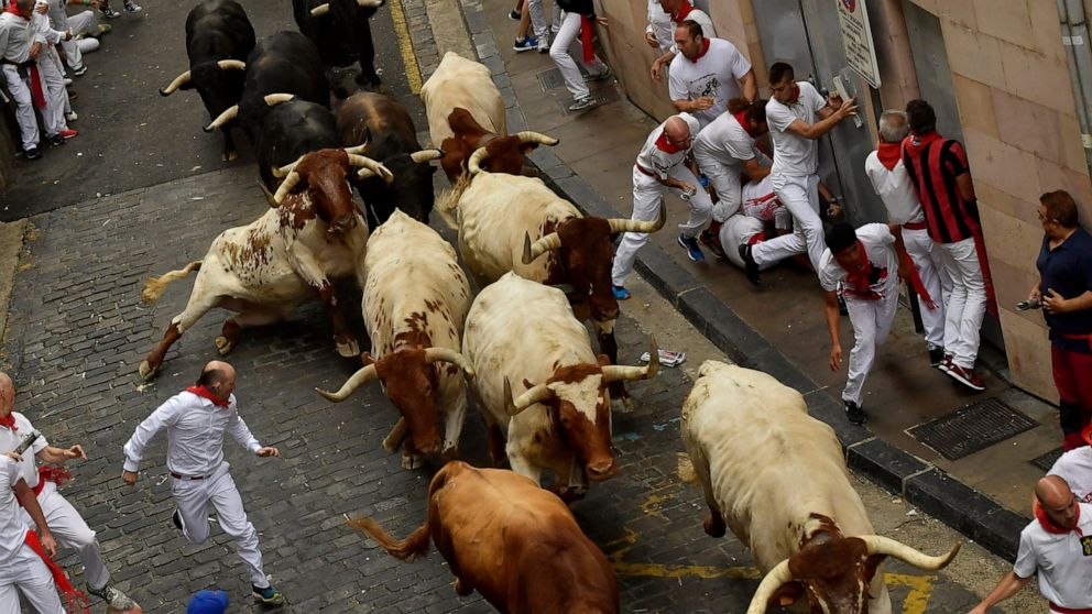 Revellers run next to fighting bulls during the running of the bulls at the San Fermin Festival, in Pamplona, northern Spain, Sunday, July 7, 2019. Revellers from around the world flock to Pamplona every year to take part in the eight days of the run