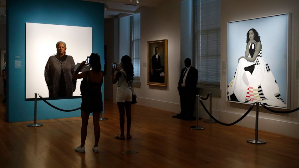 Visitors photograph a portrait of Nobel laureate Toni Morrison, painted by the artist Robert McCurdy, Tuesday, Aug. 6, 2019, near a portrait of former first lady Michelle Obama, painted by the artist Amy Sherald, at the National Portrait Gallery in W