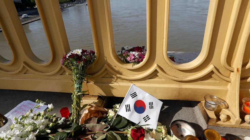FILE - In this Saturday, June 1, 2019 file photo, flowers and flag of South Korea are laid on the Margit Bridge where a sightseeing boat capsized in Budapest, Hungary. Hungarian police say a South Korean woman recovered from the Danube River has been