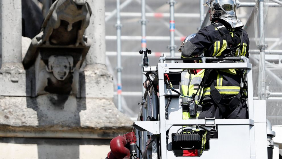 A firefighter watches a preserved gargoyle of Notre Dame cathedral Wednesday, April 17, 2019 in Paris. Notre Dame Cathedral would have been completely burned to the ground in a "chain reaction collapse" had firefighters not moved rapidly in deploying