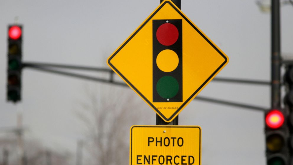 FILE - In this Tuesday, Feb. 10, 2015 file photo, a sign warns motorists of the presence of a red light camera in Chicago. Texas Gov. Greg Abbott signed a law Saturday, June 1, 2019 that bans red-light traffic cameras in Texas. (AP Photo/M. Spencer G