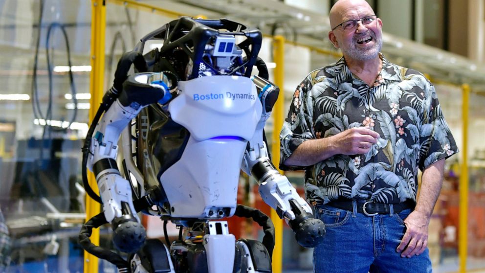 Marc Raibert, founder and chair of Boston Dynamics stands beside one of the company's Atlas robots during an interview and demonstration, Wednesday, Jan. 13, 2021, at their facilities in Waltham, Mass. The company engineered the robot to be able to d