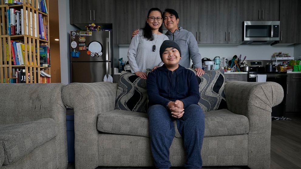 Jefferson Union High School District math teacher Eleonor Obedoza, her husband Arman and son Angelo, 12, pose for a photograph inside their new three-bedroom apartment in Daly City, Calif., Friday, July 8, 2022. The school district in San Mateo Count