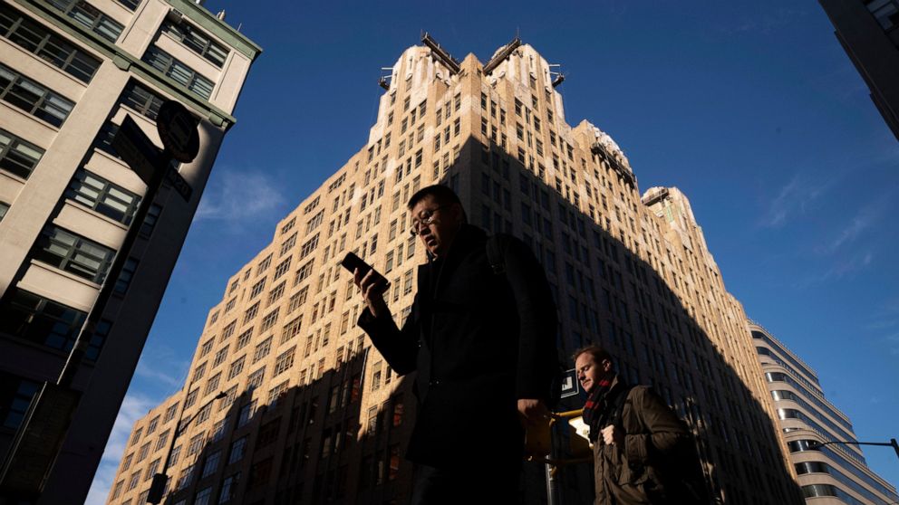 FILE - In this Dec. 17, 2018, file photo people walk by a building in New York. You carry your smartphone everywhere. But the way you use it could leave you vulnerable to specific forms of identity theft, including robocall scams and hackers looking 