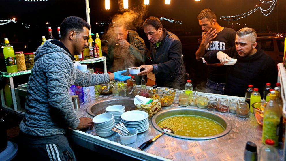 In this Feb. 13, 2019 photo, a chickpea soup vendor serves customers at a roadside stand, Tahrir Square, in Baghdad, Iraq. For the first time in years, Iraq is not at war. The defeat of the Islamic State group in late 2017 after a ruinous four-year c