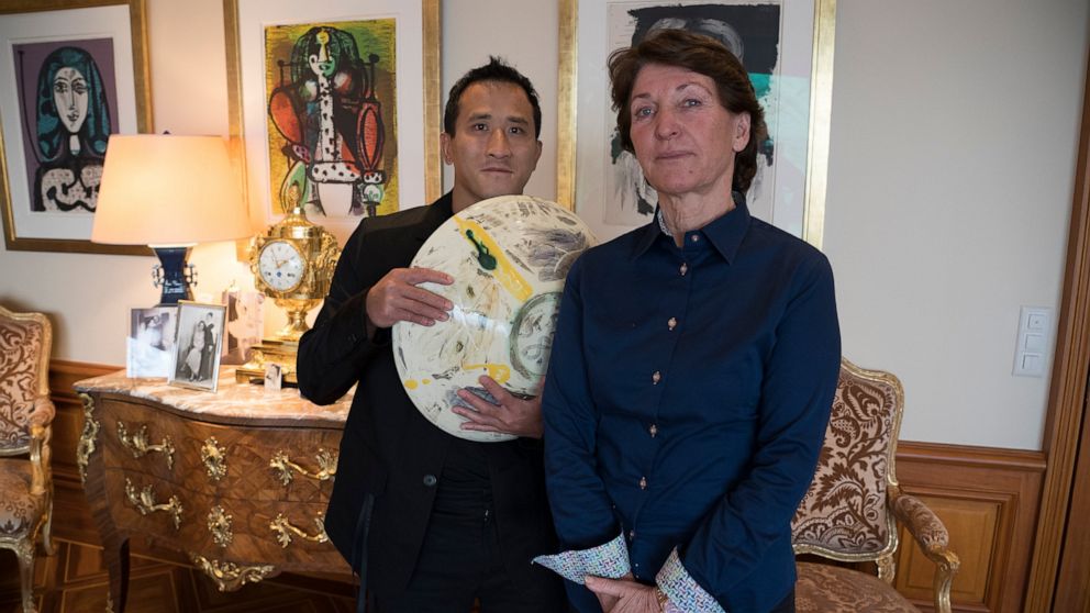 Marina Picasso, right, granddaughter of artist Pablo Picasso, and her son Florian Picasso pose with a ceramic art-work of Pablo Picasso in Cologny near in Geneva, Switzerland, Tuesday, Jan. 25, 2022. Heirs of Pablo Picasso, the famed 20th-century Spa