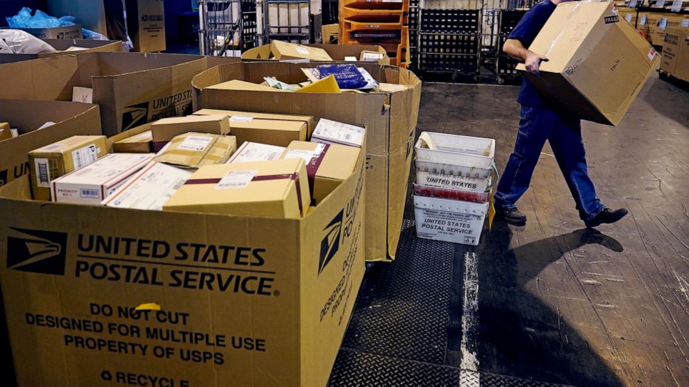 A worker carries a large parcel at the United States Postal Service sorting and processing facility, Thursday, Nov. 18, 2021, in Boston. Last year's holiday season was far from the most wonderful time of the year for the beleaguered U.S. Postal Servi