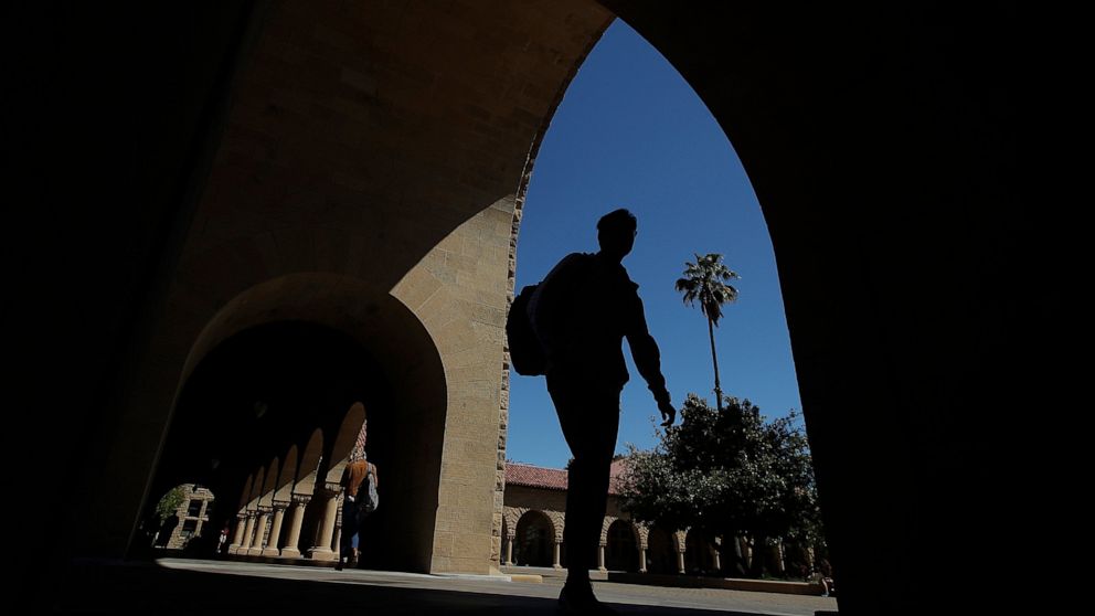 FILE - In this April 9, 2019, file photo, pedestrians walk on the campus at Stanford University in Stanford, Calif. College students who earned money this summer can make the most of it by including a few longer-term financial goals in their budgetin