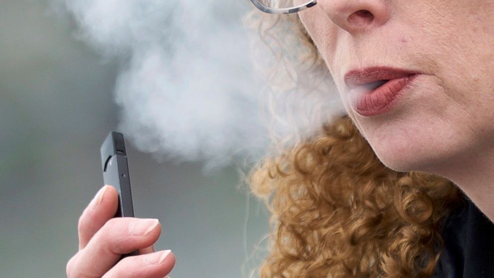 FILE - In this April 16, 2019 file photo, a woman exhales while vaping from a Juul pen e-cigarette in Vancouver, Wash. Schools have been wrestling with how to balance discipline with treatment in their response to the soaring numbers of vaping studen