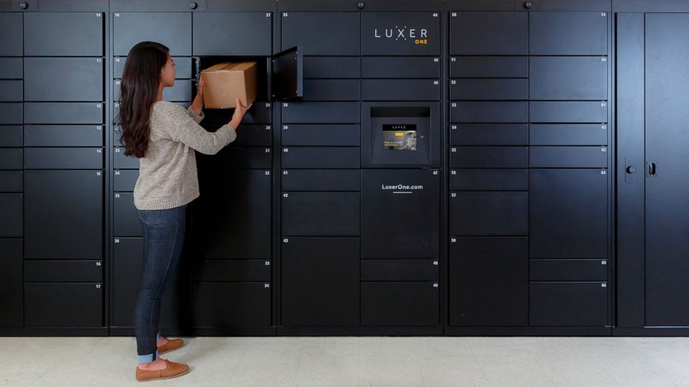 This photo provided by Luxer One shows a woman removing a package from one of Luxer's access lockers in San Francisco, Calif. Luxer One provides secure lockers in buildings in the United States and Canada that can be accessed by both delivery compani