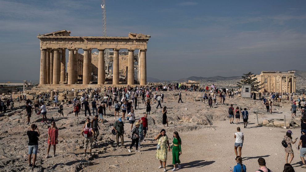 Tourists visit the Acropolis hill with the 2,500-year-old Parthenon temple on the left, and the ancient Erechtheion temple on the right, in Athens , on Tuesday, Oct. 11, 2022. Greece is on course to beat its annual record for tourism revenue as south