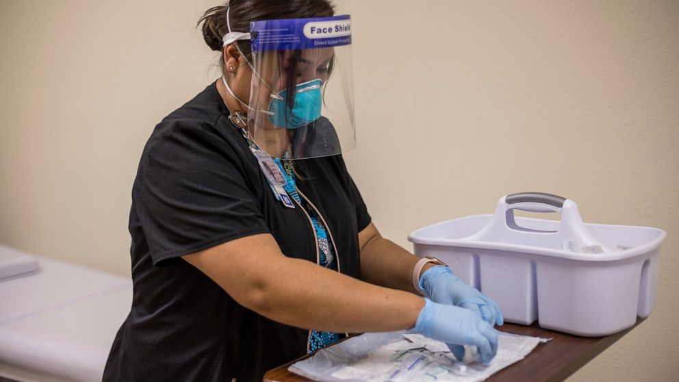 In this Tuesday, Dec. 29, 2020, photo provided by Johns Hopkins Center for American Indian Health, registered nurse Starla Garcia prepares a coronavirus vaccine in Chinle, Ariz., for someone who enrolled in the COVID-19 vaccine trials on the Navajo N