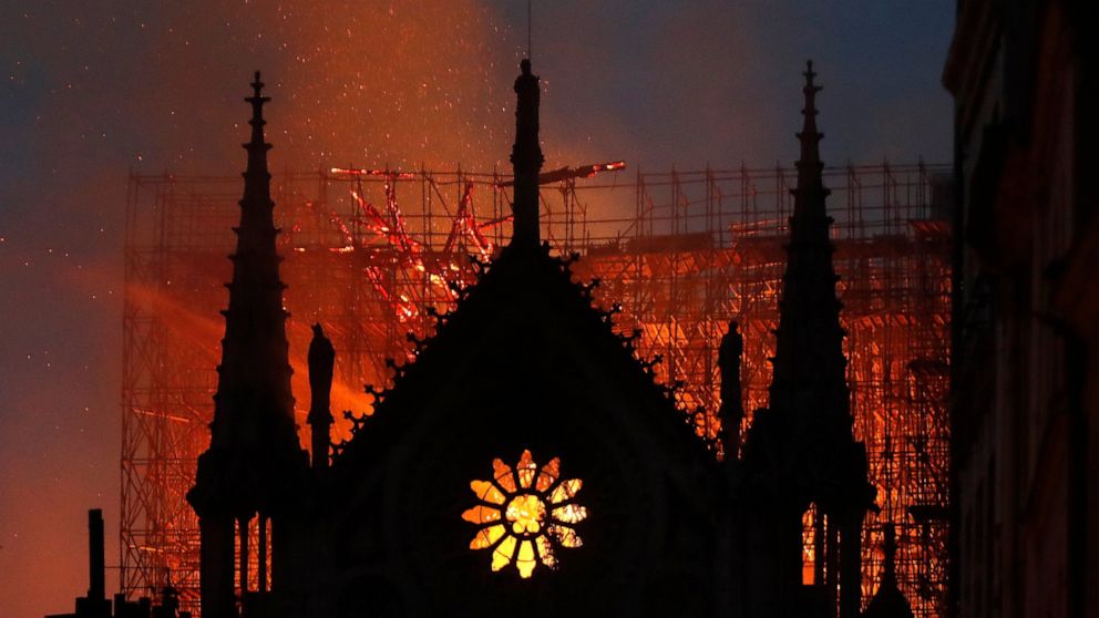 Flames and smoke rise from Notre Dame cathedral as it burns in Paris, Monday, April 15, 2019. Massive plumes of yellow brown smoke is filling the air above Notre Dame Cathedral and ash is falling on tourists and others around the island that marks th