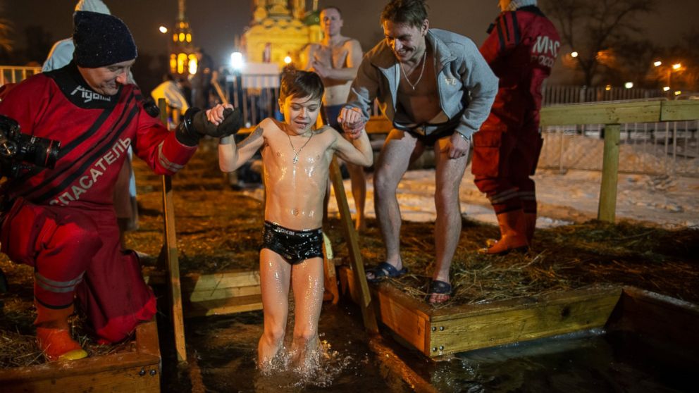 Russian Emergency Situations employees help a boy to bath in the icy water on Epiphany at the Church of the Holy Trinity in Ostankino near TV Tower in Moscow, Russia, Friday, Jan. 18, 2019. Across Russia, the devout and the daring are observing the O