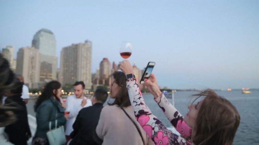 A guest at the La Nuit en Rosé festival in New York City snaps a photo of her glass of Rosé.