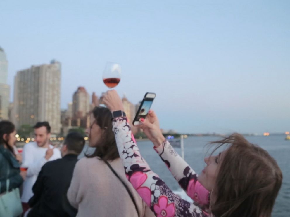 A guest at the La Nuit en Rosé festival in New York City snaps a photo of her glass of Rosé.