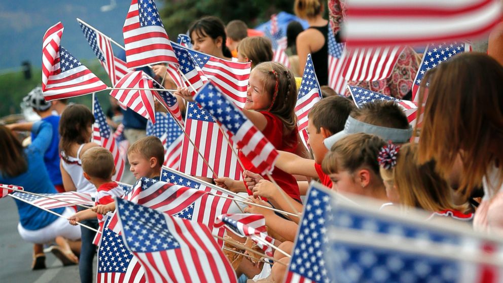People wave flags as the Independence Day parade rolls down Main Street, July 4, 2014, in Eagar, Ariz. The Northern Arizona town celebrates the Fourth of July annually with a parade and fireworks. 