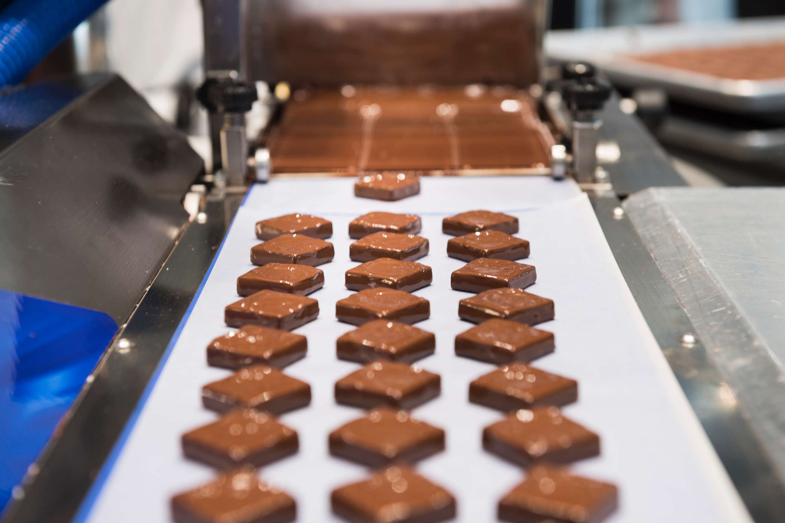 PHOTO: At Kreuther Handcrafted Chocolate, an enrobing machine at work making specialty chocolates. 