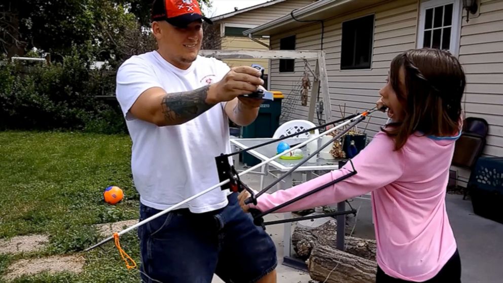 PHOTO: Jason McDonald films his daughter Alexis as she readies the slingshot that she is using as a way of removing one of her last few baby teeth.