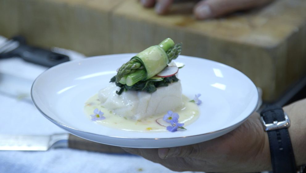 PHOTO: Chilean sea bass with spinach, asparagus and edible flowers steeped in sauce.